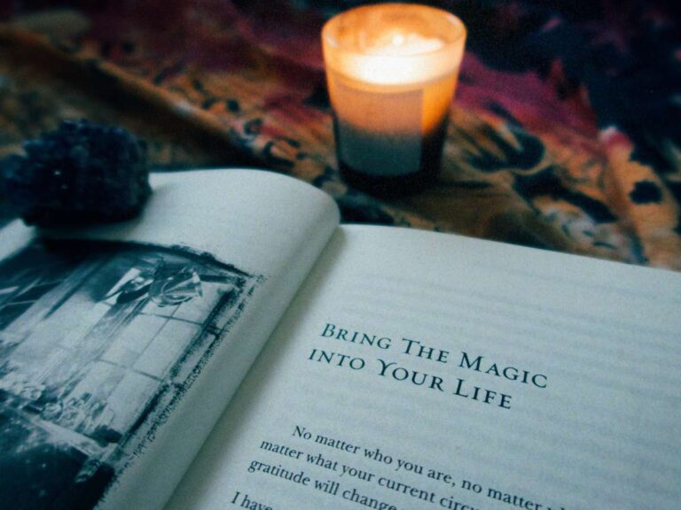 An open page by candlelight with an amethyst to represent Lucie's latest blog post, The Magic by Rhonda Byrne | Review and lessons