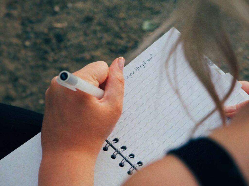 Lucie writing in a notebook outdoors to signify adopting the slow living lifestyle