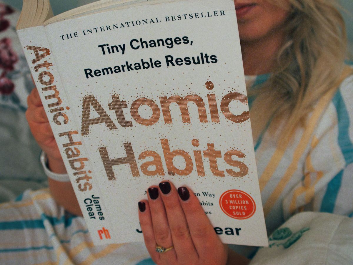 A close-up photo of Lucie reading Atomic Habits, ahead of giving an Atomic Habits review