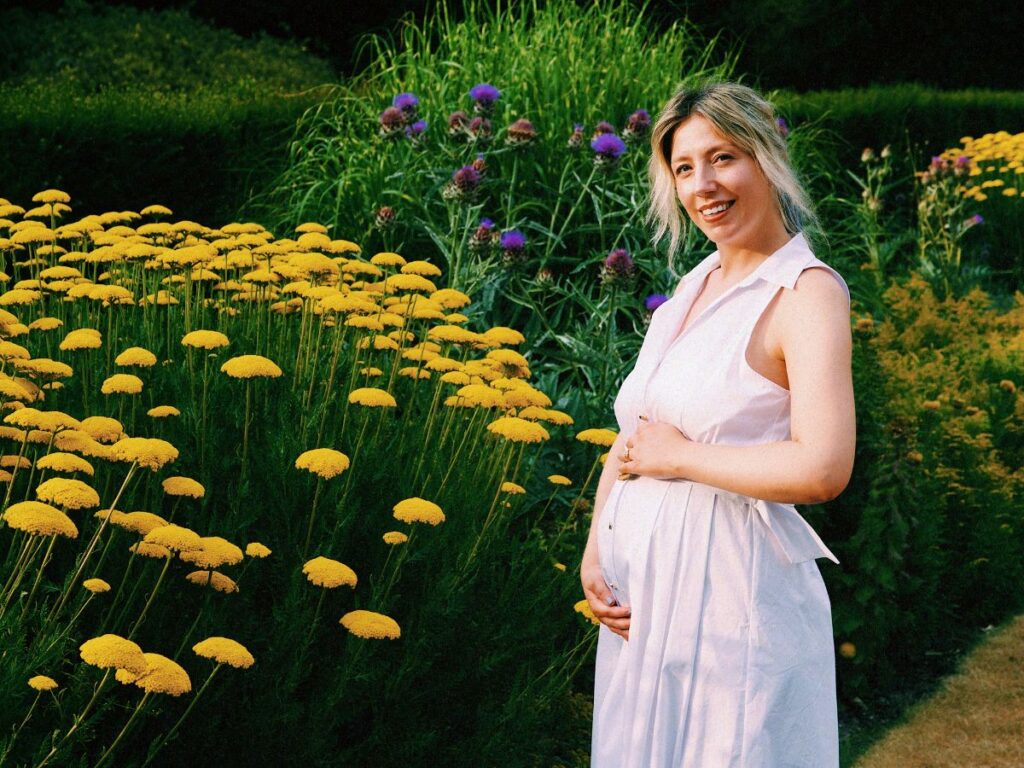 Lucie posing by flowers at Tylney Hall when over halfway through pregnancy